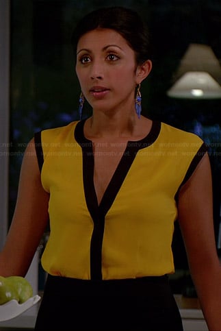 Divya's yellow top with black trim and blue earrings on Royal Pains