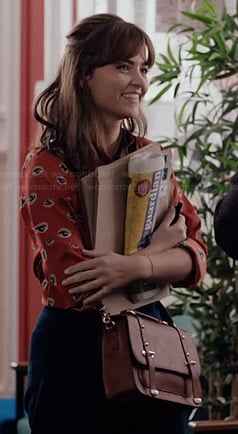 Clara's orange eye print shirt and tan bag on Doctor Who