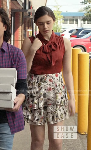 Nia’s floral skirt and red tie neck blouse on Supergirl