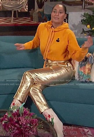 Tracee Ellis Ross’s yellow hoodie, gold pants, and floral boots on Busy Tonight