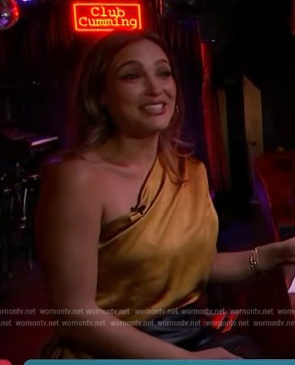 Emily Orozco’s gold satin one shoulder top on Access Hollywood