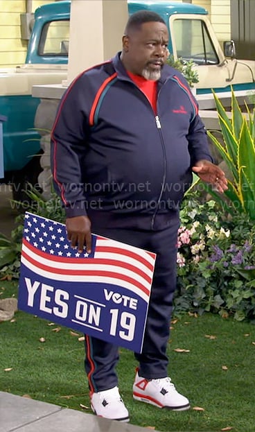 Calvin’s navy tracksuit with red and green stripes on The Neighborhood