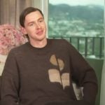 Harris Dickinson’s brown logo sweater on Access Hollywood