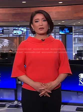 Elaine Quijano’s red roll-neck short sleeve top on CBS Evening News
