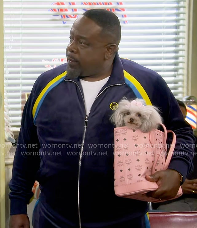Calvin's navy velour tracksuit and pink dog bag on The Neighborhood
